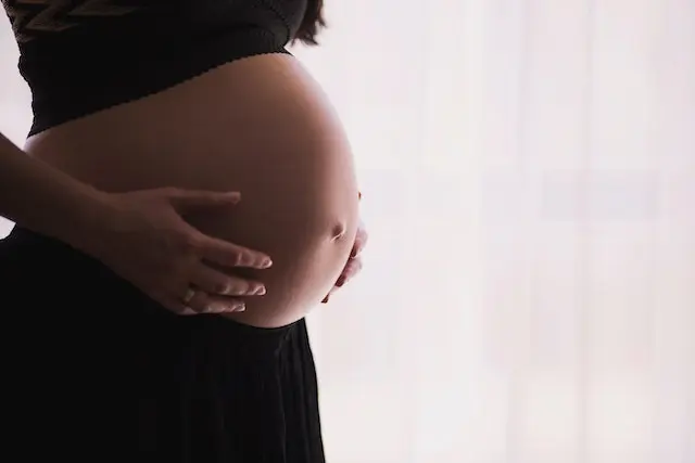 Gravid kvinde tager sig til sin mave